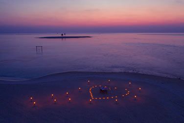 Sur le sable blanc, savourez un dner entre amoureux aux lueurs des bougies