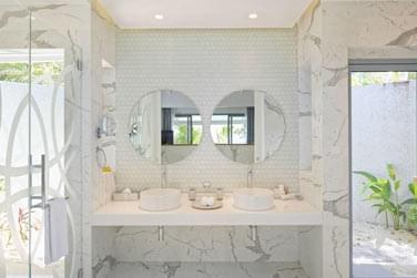 Une salle de bain luxueuses aux tons blancs et motifs marbrs se mlent