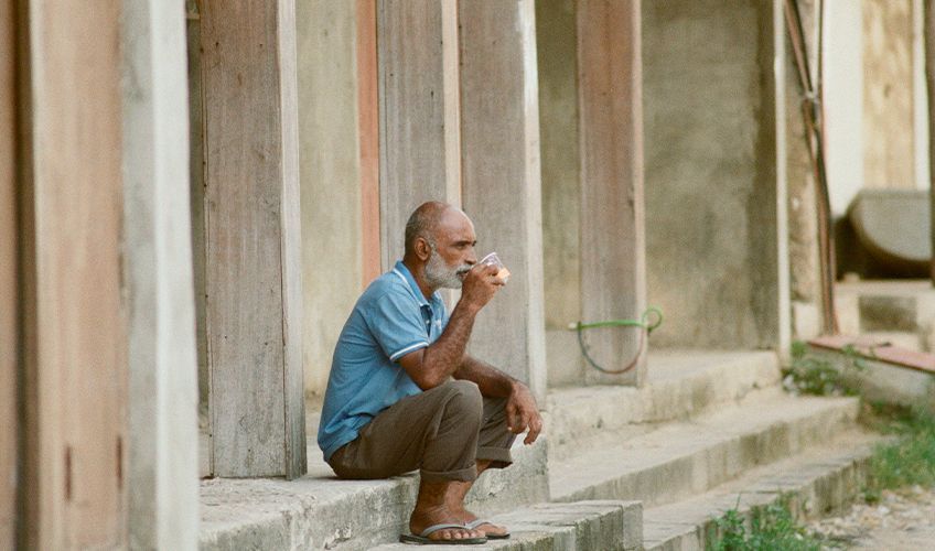 homme assis buvant son caf dans une ruelle de Stone Town